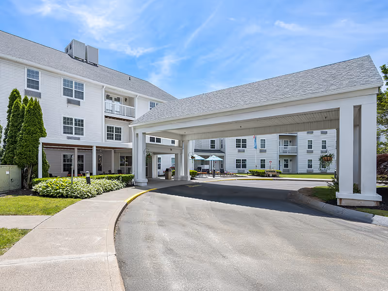 Exterior view of a senior living facility with a covered entrance and driveway.