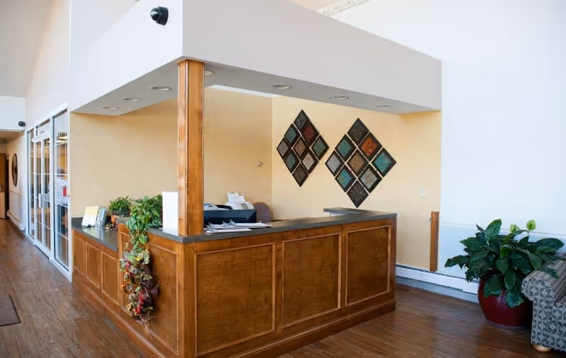 Reception desk and lobby area with a wooden front desk, decorative wall art, and potted plants.