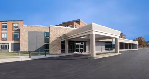 Exterior view of a modern hospital entrance with a covered drop-off area.