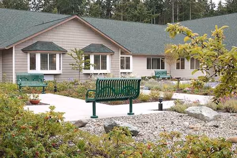 Outdoors at Sequim Health and Rehabilitation: green benches in a landscaped courtyard.