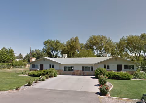Front view of a single-story senior living facility with driveway and manicured landscaping.