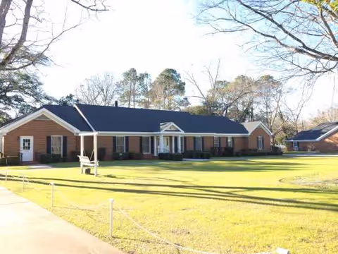 Single-story brick senior living facility with a manicured lawn and front entrance.