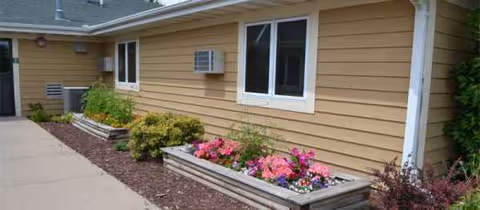 Exterior view of The Beacon at Lake Crystal with beige siding, windows, and flower planters.