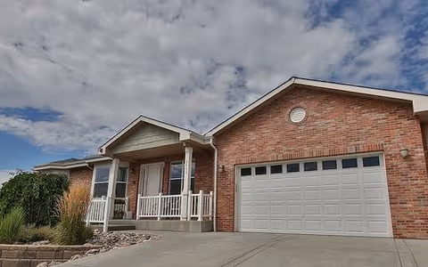 Brick exterior of a senior living facility with a driveway, porch, and attached garage.