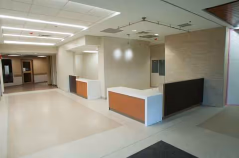 Spacious hospital lobby interior with reception desks and an empty corridor.
