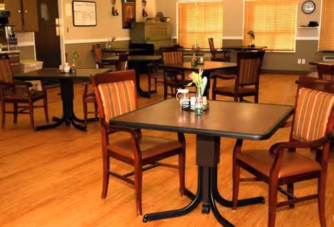 Dining room with several tables and chairs in a senior living facility.