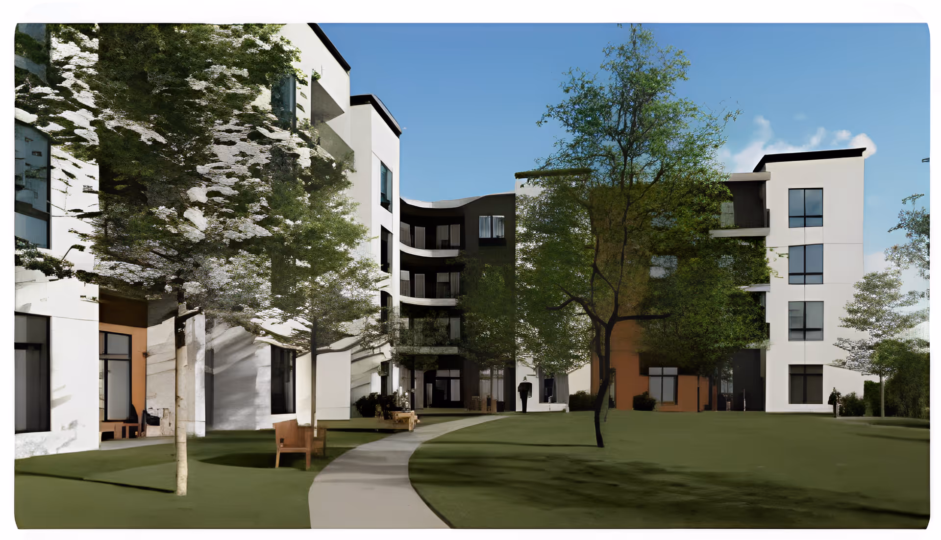Outdoor courtyard area of The Delaney at the Vale senior living facility featuring a curved walkway, green lawn, several trees, benches, and a multi-story white building with large windows under a clear blue sky.