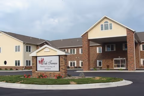 Exterior view of Oak Terrace Senior Living of Jordan with brick entrance and sign.