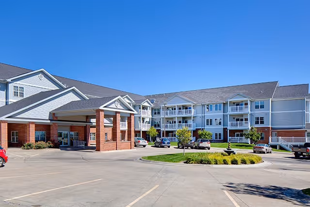 Exterior view of Kinship Pointe Northridge facility with entrance and parked cars.