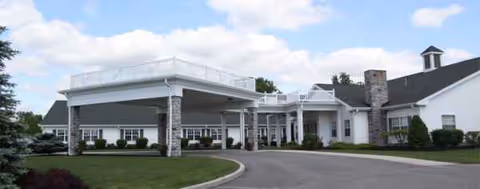 White senior care facility with a covered entrance and circular driveway.