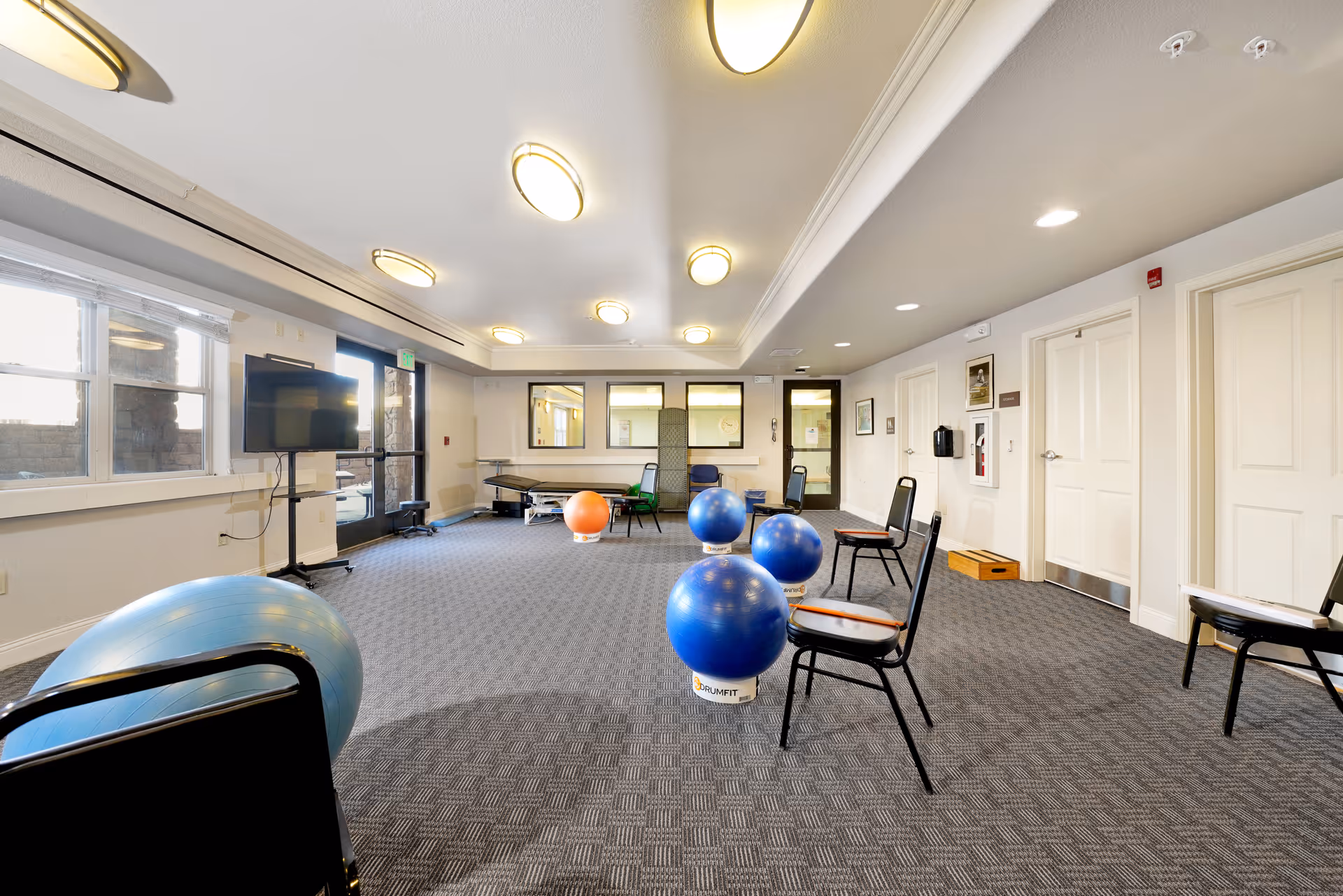 A spacious interior activity room with chairs and large exercise balls arranged for a fitness class.