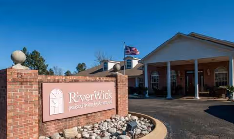 Exterior of RiverWick assisted living facility with brick sign and flag.