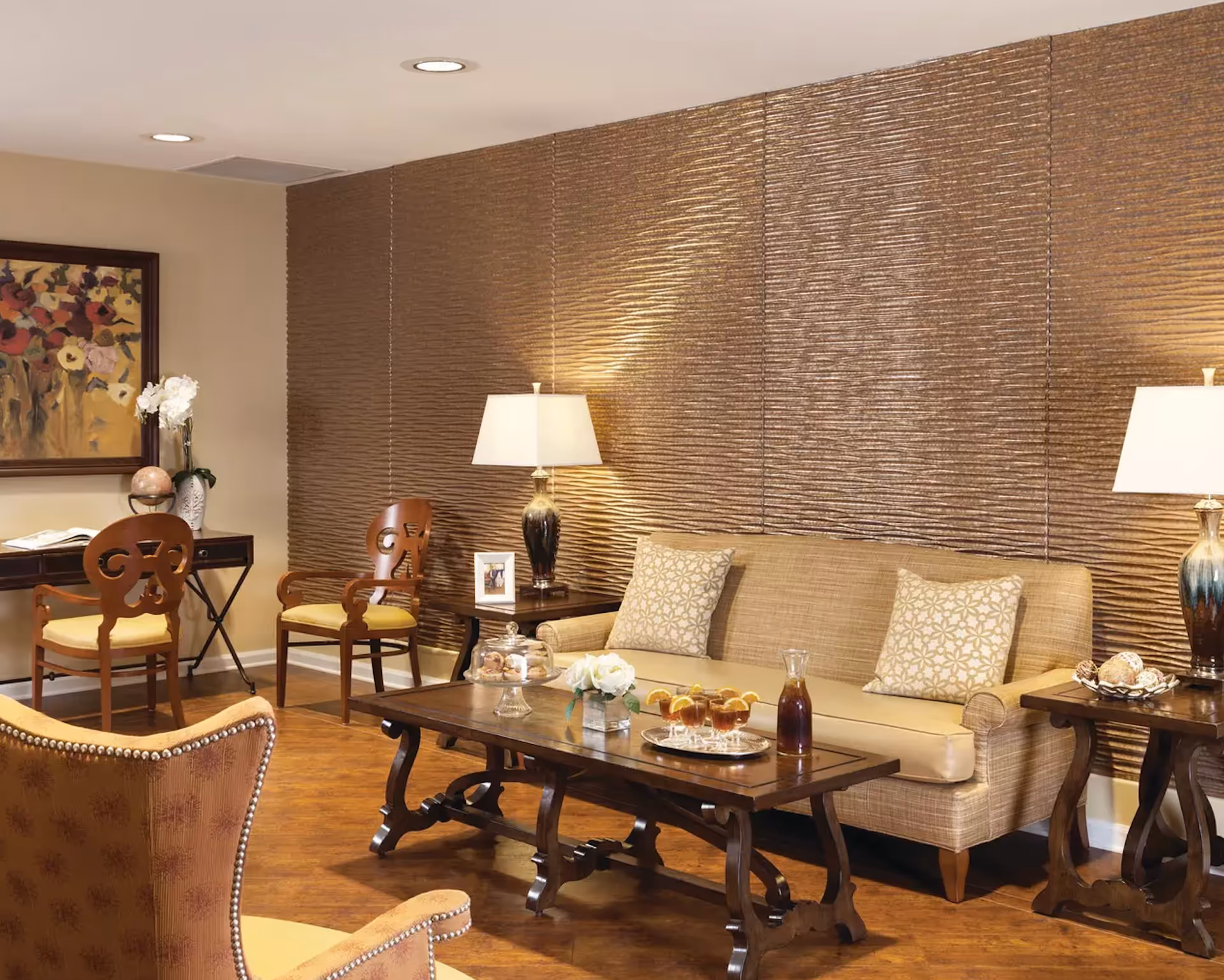 Comfortable living room lounge with a beige sofa, patterned pillows, wooden coffee table and chairs against a textured accent wall.