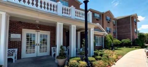 Exterior view of Brookdale Westover Hills entrance with brick facade, white columns, glass doors, and landscaping.