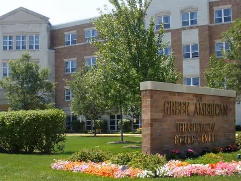 Exterior view of Greek American Rehabilitation & Care Centre with sign and landscaped grounds.