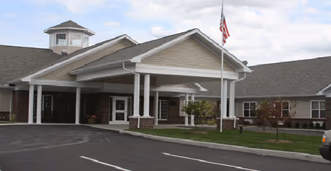 Exterior view of The Oaks at Woodfield with front entrance and flagpole.