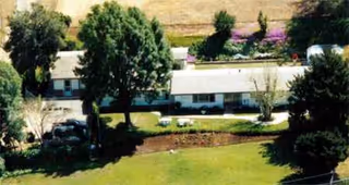 Exterior of a senior living facility with windows, trees, and a manicured lawn.