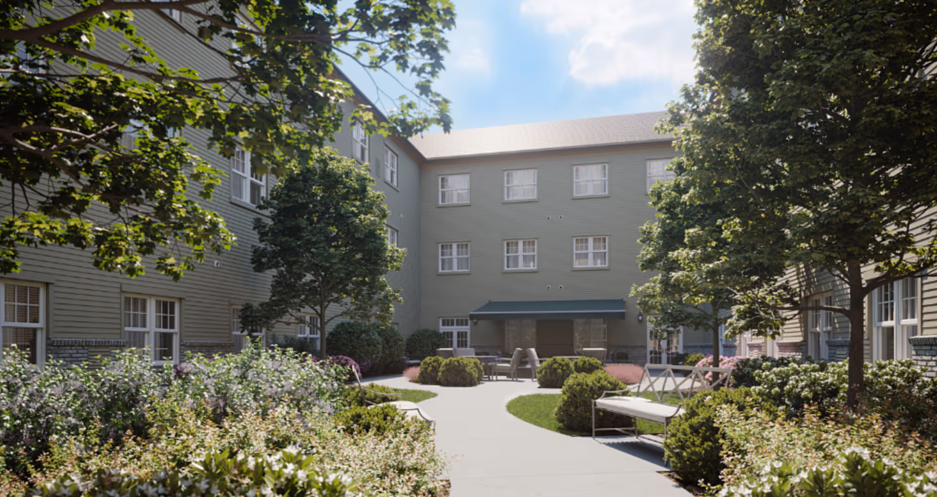 Sunlit landscaped courtyard with benches and walkways surrounded by a three-story residential building and trees.