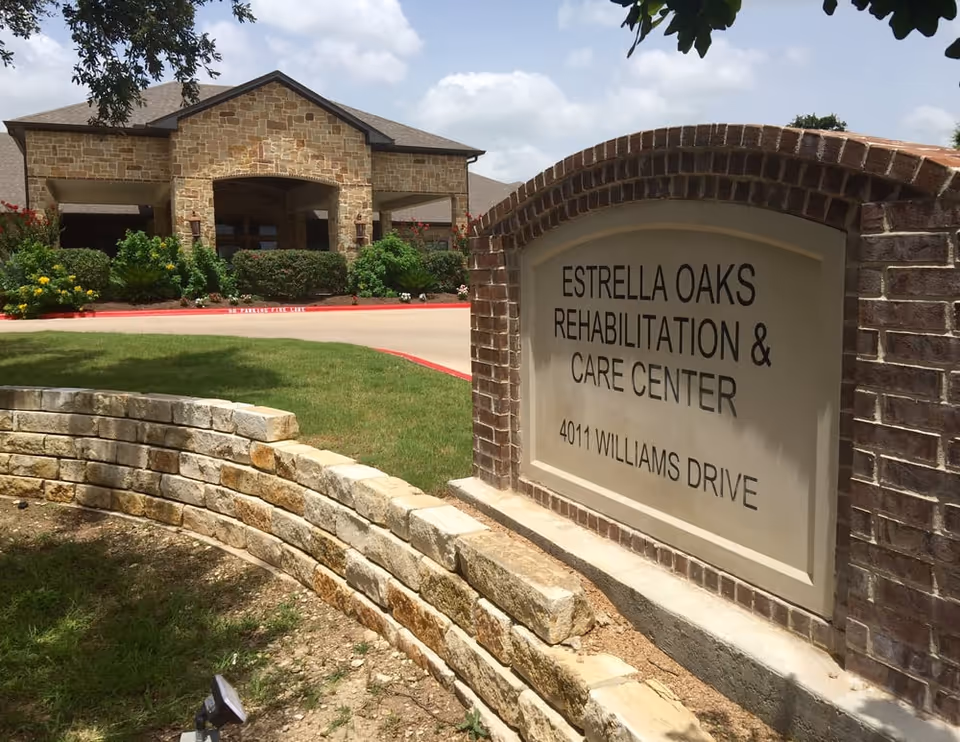 Stone building entrance and brick sign for Estrella Oaks Rehabilitation and Care Center.