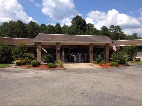 Front view of Tishomingo Manor entrance with landscaping and American flag.
