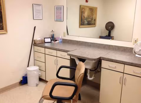 A salon chair beside a long counter and mirror in a clinical grooming area.