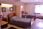 A shared bedroom with two twin beds, nightstands, a privacy curtain, and a window with curtains.