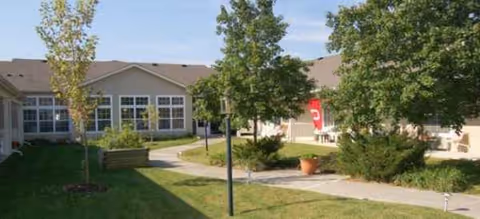 Brookdale Westerville exterior with courtyard, walkway, trees, and the front of the building.