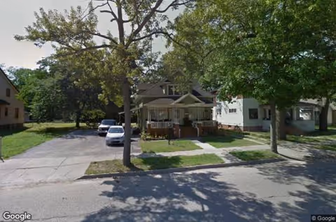 Front view of Morning Glory Adult Foster Care house with porch, trees, and parked cars.