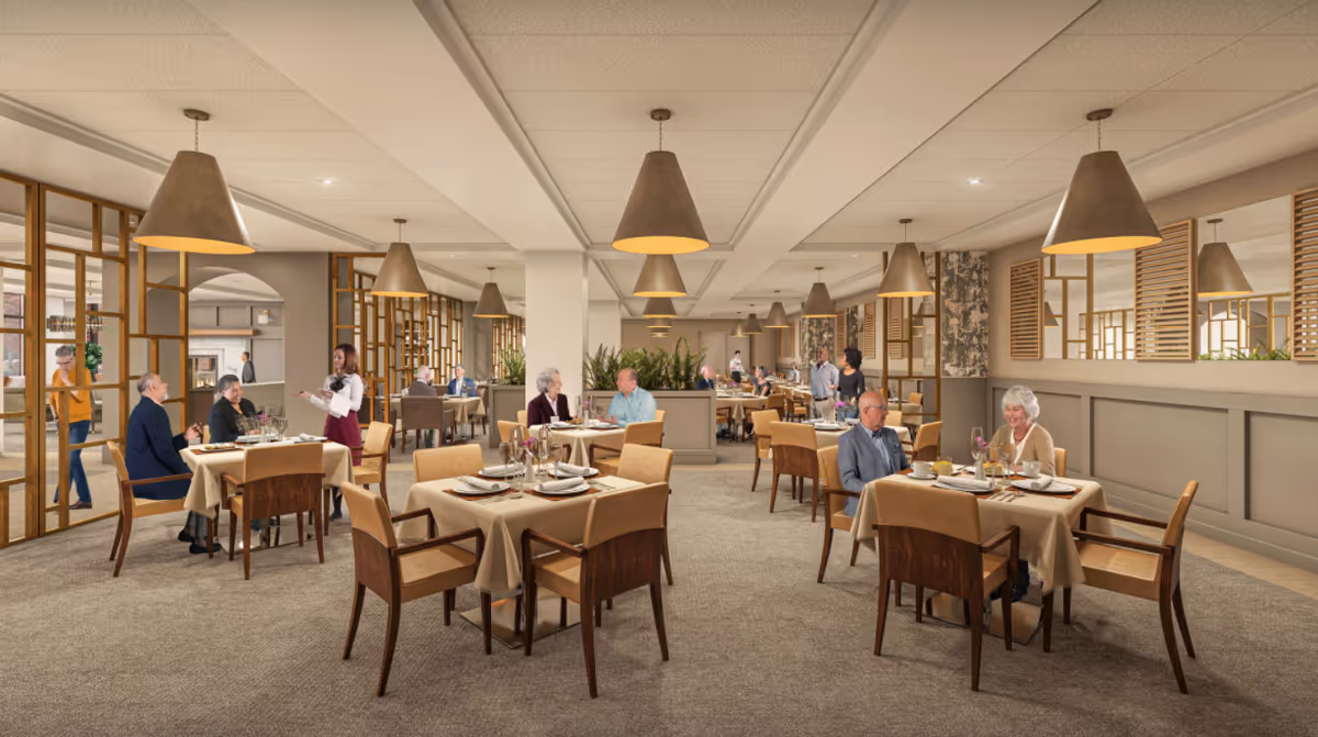 Spacious, well-lit dining room with multiple set tables, pendant lights, and seniors dining while staff serve them.