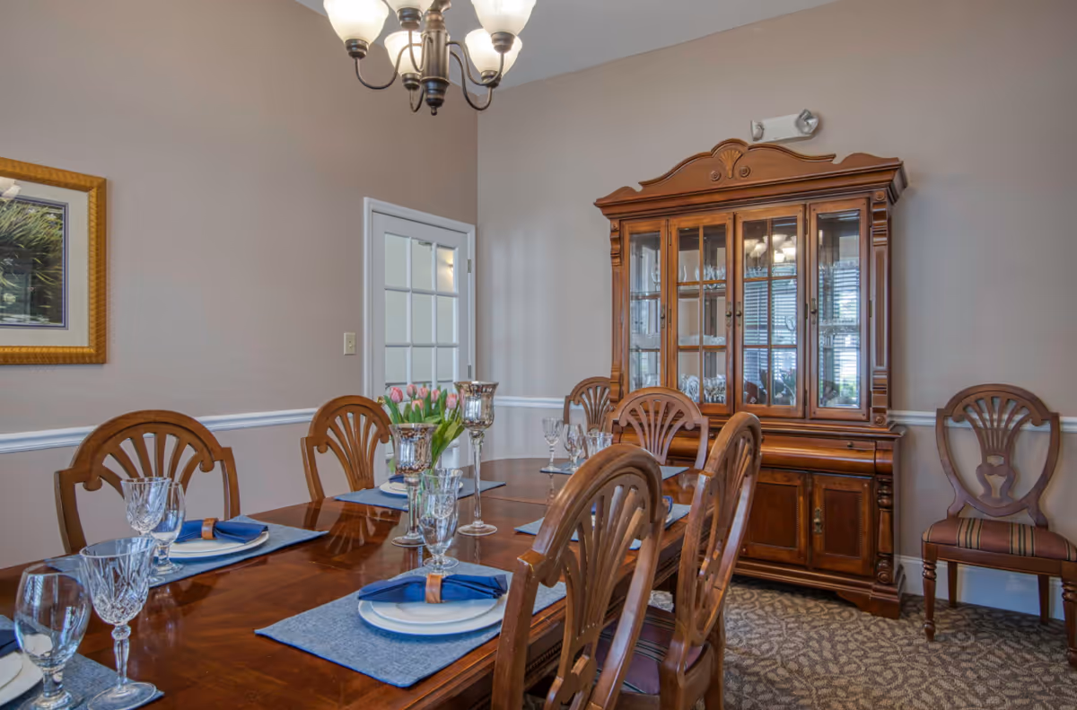 Formal dining room with a wooden table set with glassware and place settings and a china cabinet against the wall.