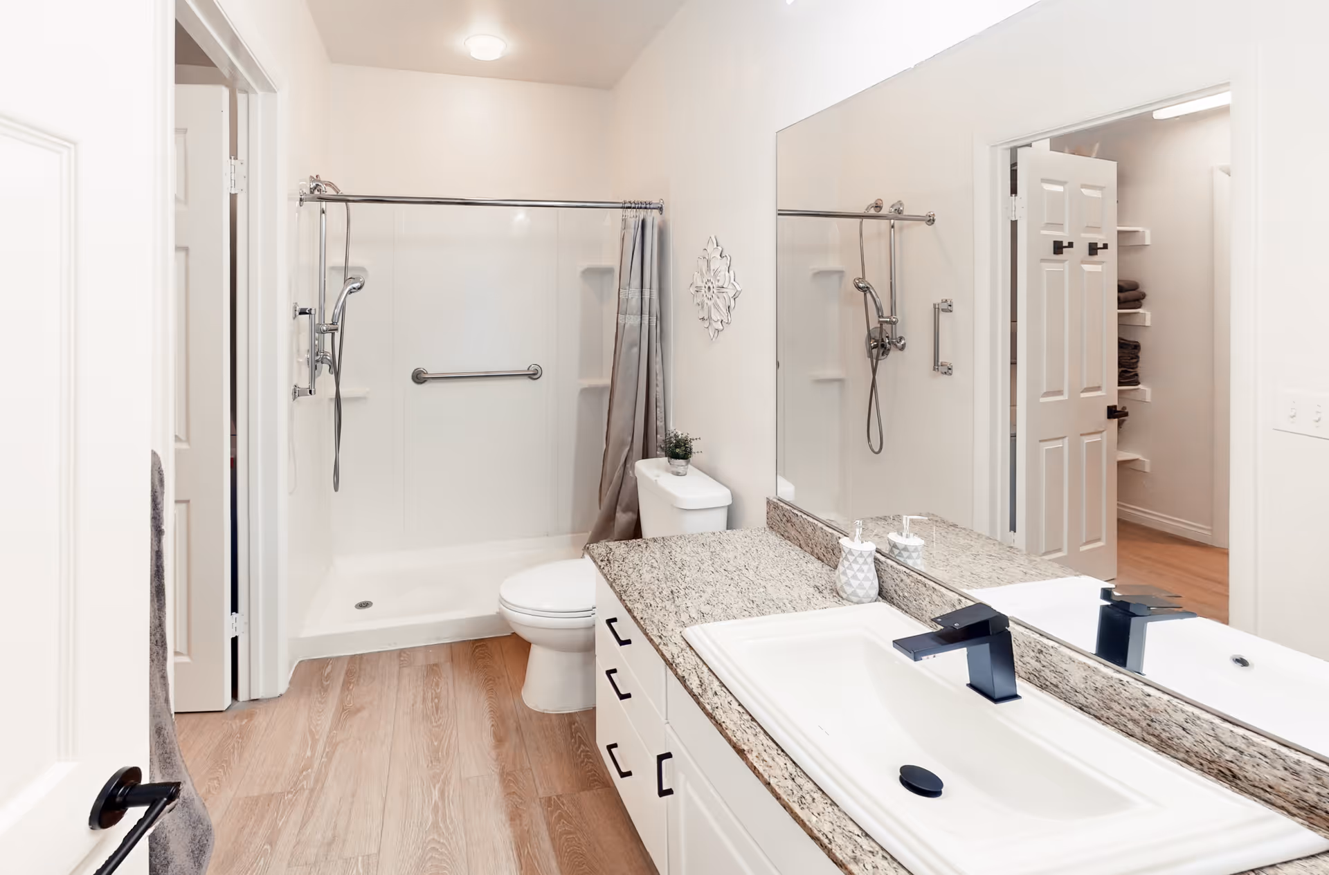 Bright modern bathroom with a walk-in shower, toilet, sink and large mirror.