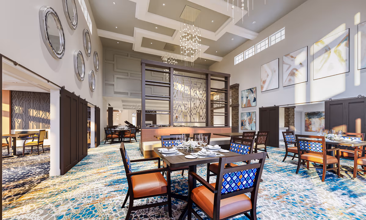 A spacious and elegant dining room with high ceilings and large windows letting in natural light. The room features multiple dining tables set with white plates, glasses, and napkins. Chairs have blue patterned backs and orange seats. The carpet has a colorful abstract pattern. Decorative mirrors and abstract paintings adorn the walls, and modern chandeliers hang from the ceiling.