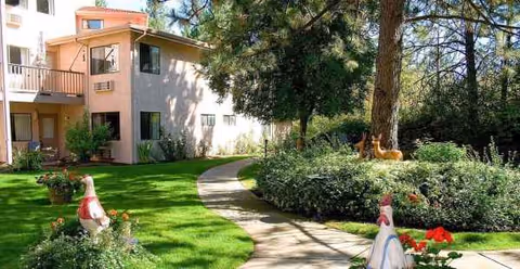 Exterior view of Solista Spokane with a curved path, lawn, trees, and a peach building.