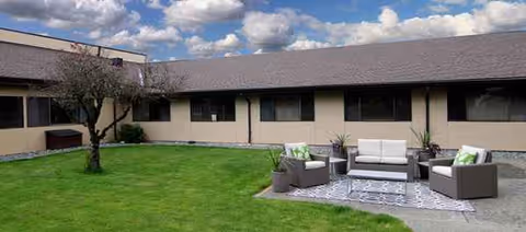 Exterior courtyard of the facility with a grassy lawn and patio seating.
