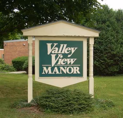 Front sign for Valley View Manor Nursing Home, surrounded by trees.