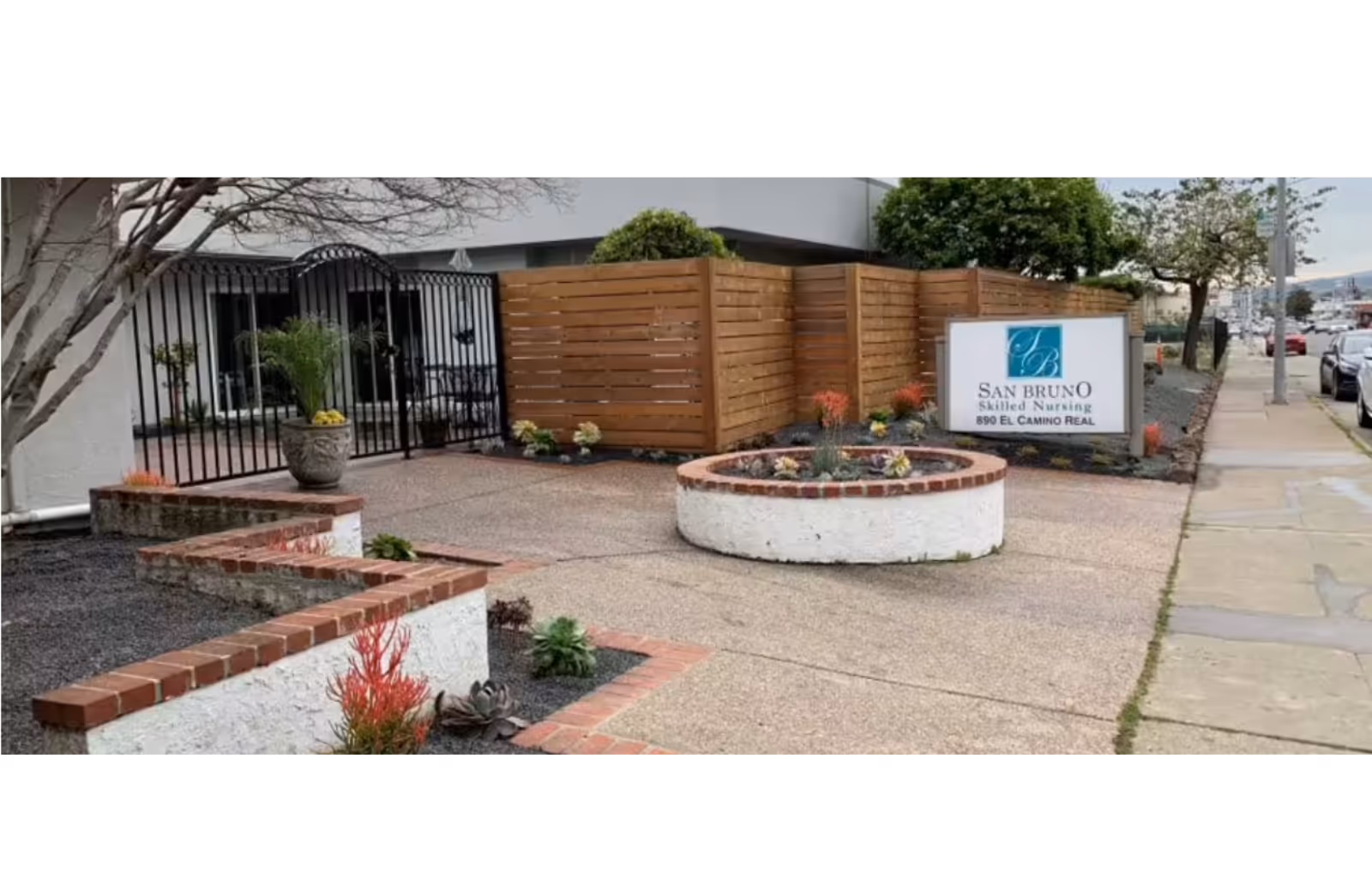 Exterior view of the San Bruno Skilled Nursing facility, featuring a gated entrance and landscaped area.