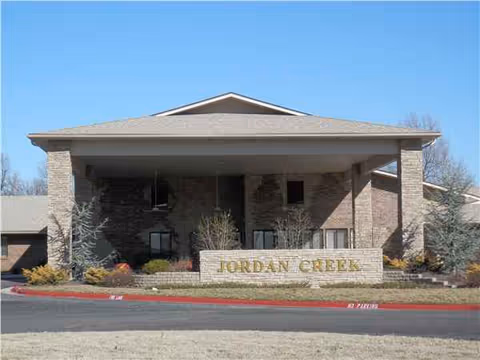 Front view of brick senior living facility with a large covered entrance and Jordan Creek sign.