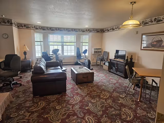 Prairie View Senior Living common living room with sofa, chairs, coffee table, and TV.