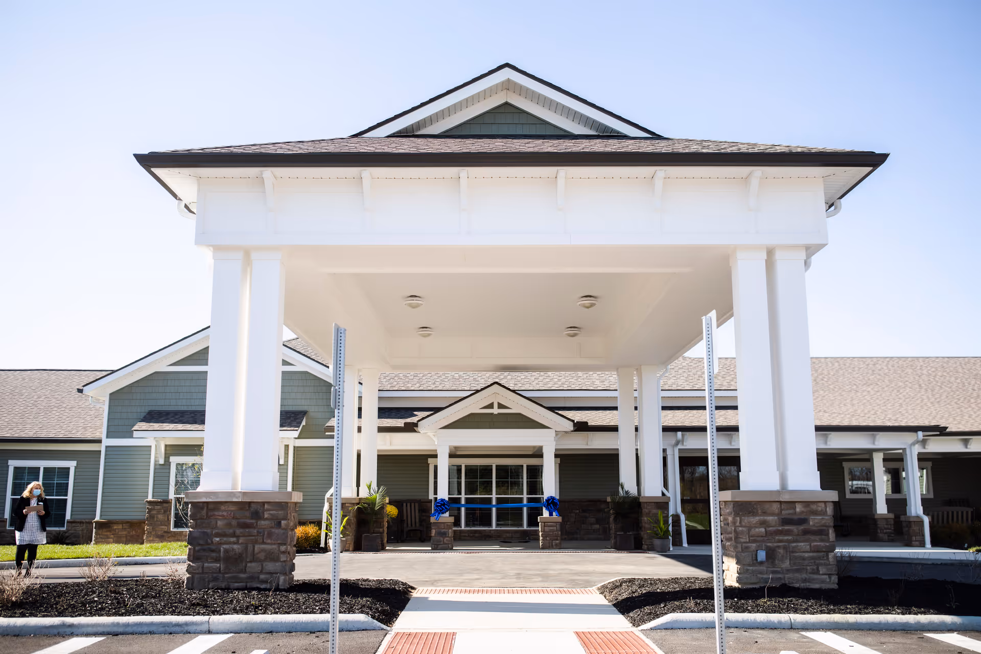 Front entrance of a single-story senior living facility with a covered porte-cochere supported by white columns.