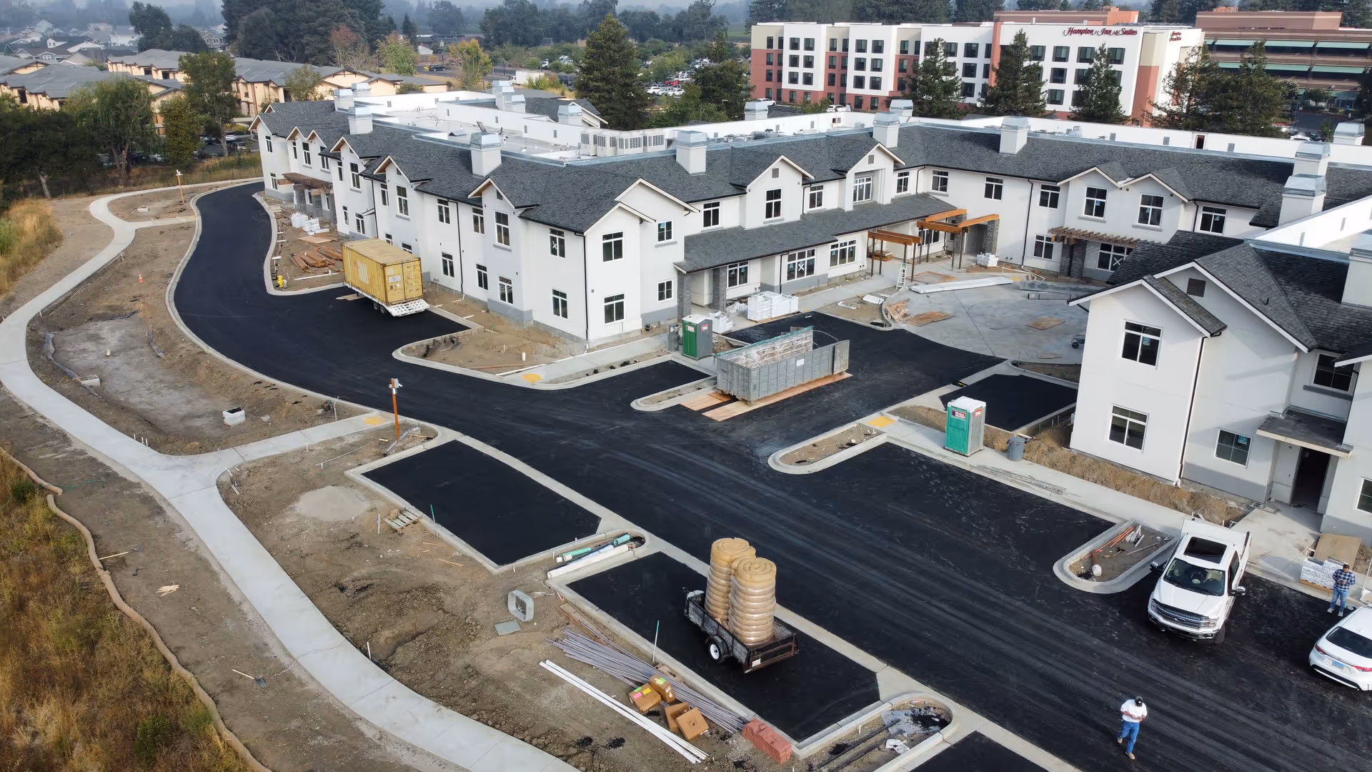 Aerial view of the Santa Rosa Hills Senior Living building under construction with newly paved driveways, parking areas, and construction materials on site.