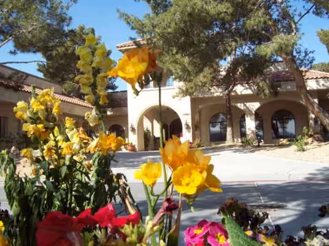 Exterior view of Mission Pines Nursing and Rehabilitation Center with arches and colorful flowers.