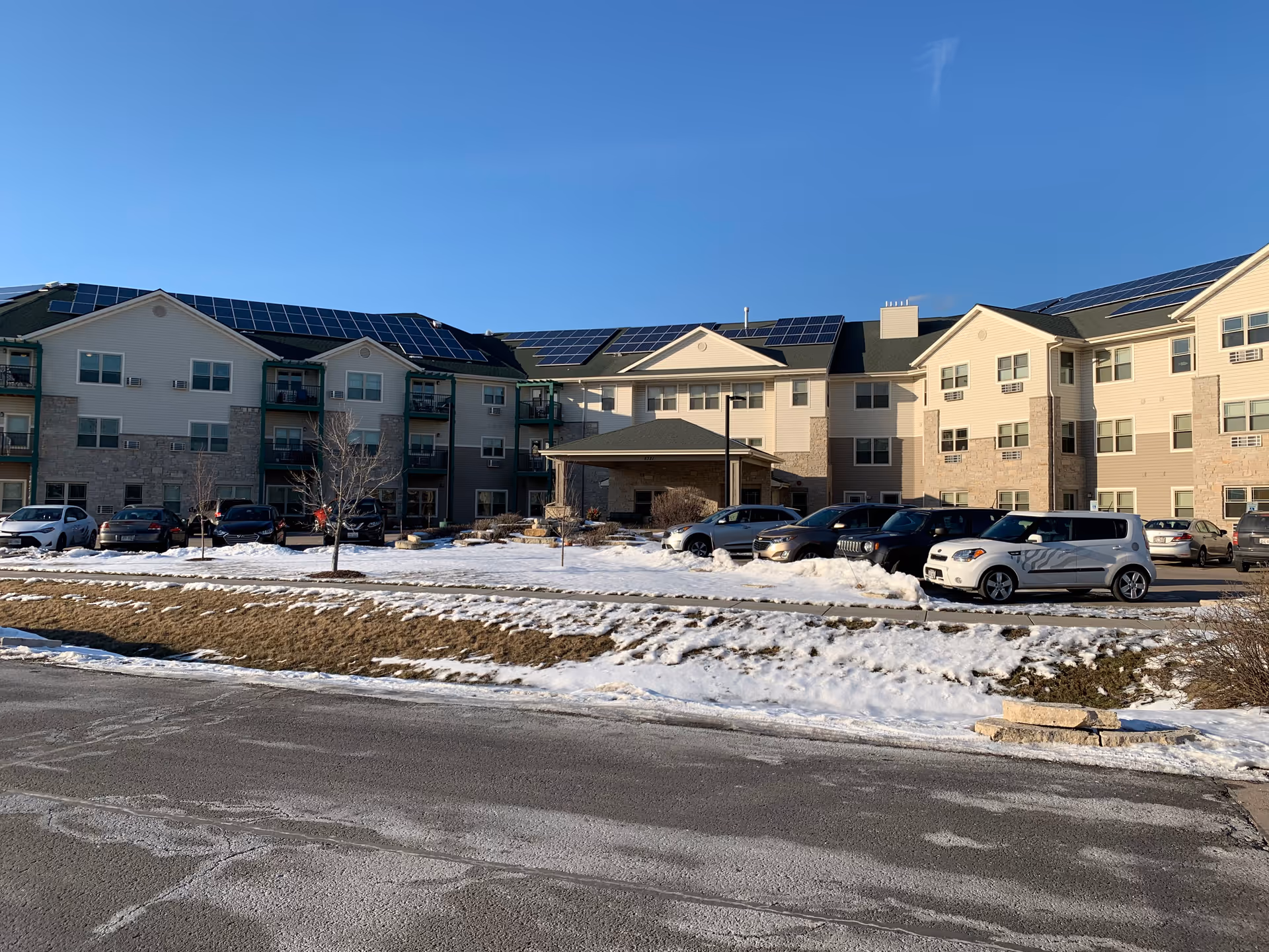 Exterior view of Parkview Gardens senior living building with parked cars and solar panels.