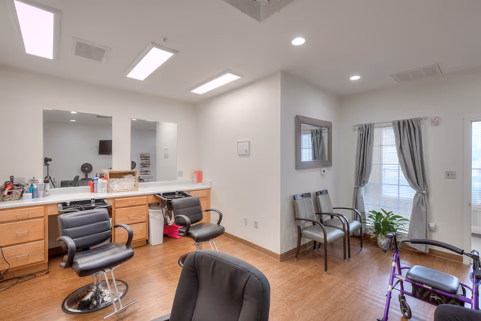 Well-lit interior salon area with styling chairs, mirrors and a countertop of supplies, plus a small seating area and a walker.