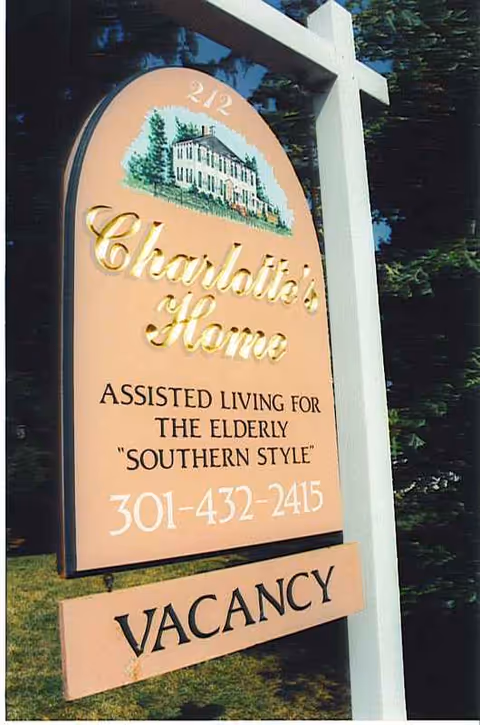 A peach-colored sign for Charlotte's Home Assisted Living with vacancy notice.