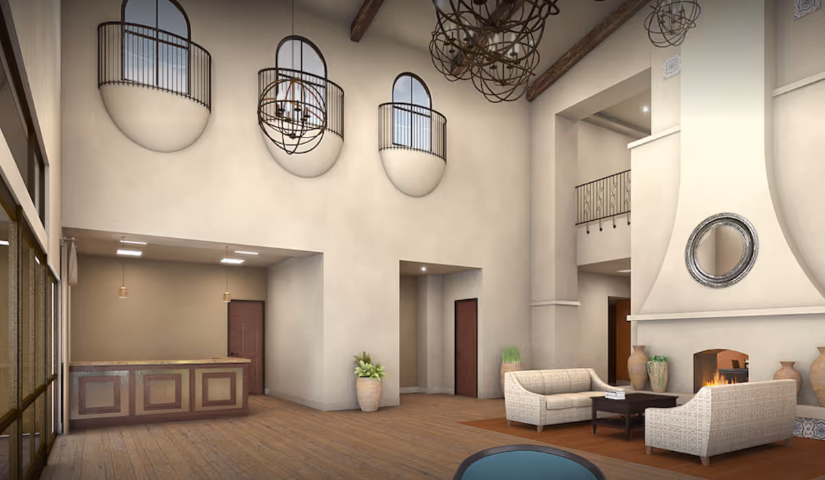 Spacious two-story lobby with seating area and fireplace, a reception desk, and decorative upper balconies.