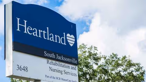 Blue Heartland sign for South Jacksonville Rehabilitation and Nursing Services outdoors near trees