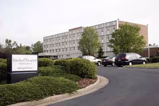 Exterior view of a multi-story hospital building with parked cars in front.