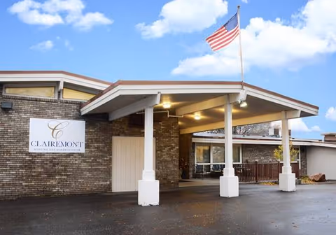 Exterior view of Clearwater Care Center with brick facade, covered entrance, and American flag.