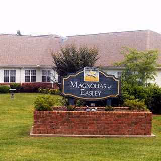 Exterior view of a senior living facility with brick planter and Magnolias at Easley sign