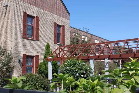 Exterior view of Brandon Woods of Dartmouth with brick walls, red shutters, and a red pergola.